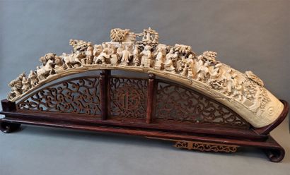 null A carved and chiseled ivory tusk decorated with numerous figures engaged in...