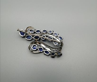 null An 18K white gold 750‰ scroll-shaped brooch set with 17 oval and brilliant sapphires...