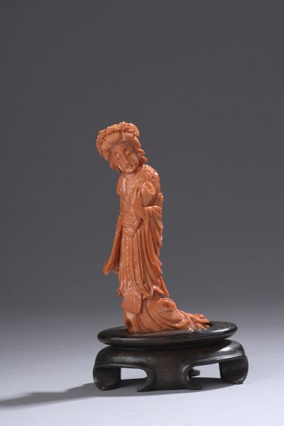 null Statuette in orange-red coral* showing a young woman standing with a scroll...