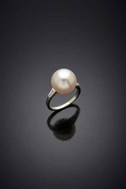 null Platinum ring 850‰, set with a fine button pearl, shouldered by two tapers diamonds....