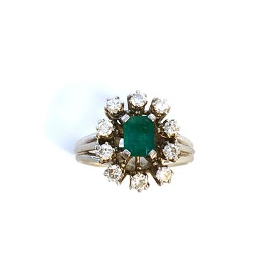 null An 18K white gold ring centered on an emerald surrounded by round diamonds.

Finger...