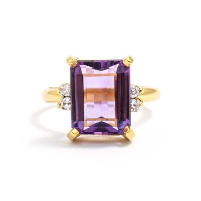 null An 18K yellow gold ring centered on an emerald-cut amethyst and set with round...