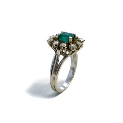 null An 18K white gold ring centered on an emerald surrounded by round diamonds.

Finger...