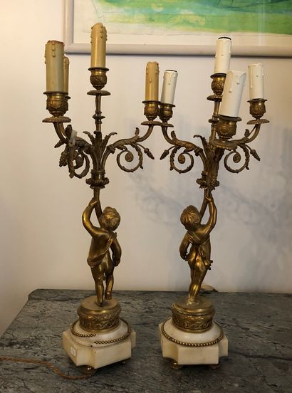 null A pair of four-armed gilt bronze candelabras, marble base, decorated with putti,...