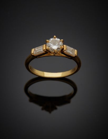  Solitaire en or jaune 18K 750‰, paré d’un diamant de taille brillant épaulé de deux...