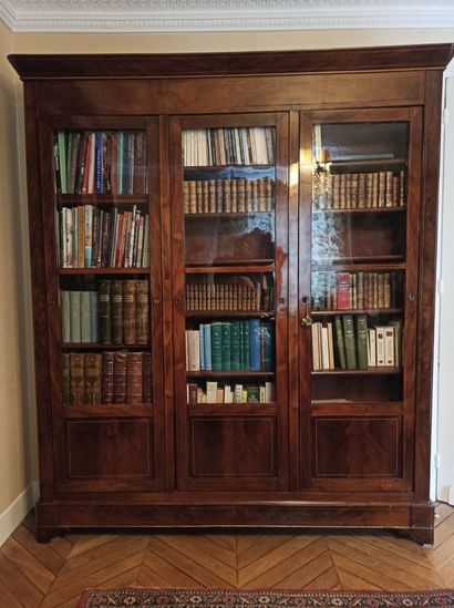 null Bookcase in flamed mahogany veneer and light fillets, opening with three doors...