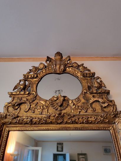null Mirror in a gilded wood frame carved with scrolls and shells. The pediment is...