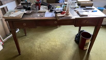 null Flat desk in wood veneer opening to three drawers in belt. Sheath feet. Leather...