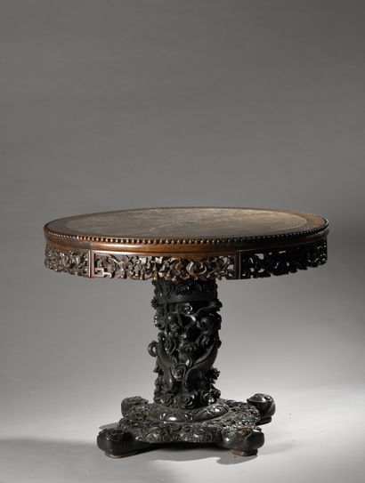 null A round table in carved and partly blackened natural wood, the top in hard stone,...