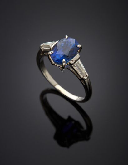 null Platinum 850‰ ring, adorned with an oval-shaped sapphire, shouldered by two...