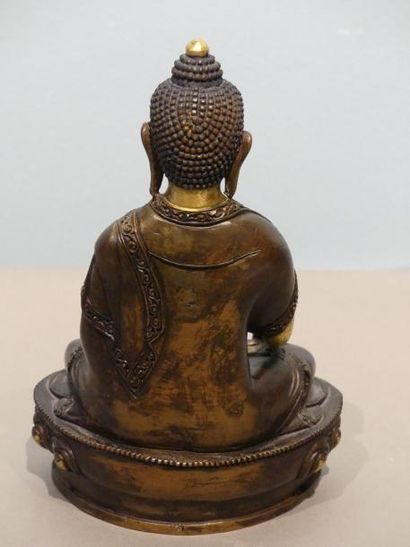 null Statuette en bronze partiellement doré, représentant le Bouddha, assis sur un...