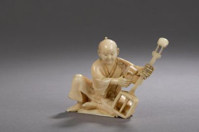 null PETIT OKIMONO en ivoire figurant un fabriquant de shamisen, accroupi à son ouvrage....