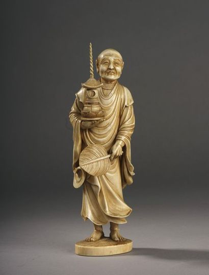 null Okimono en ivoire sculpté figurant un personnage âgé debout, une lanterne dans...