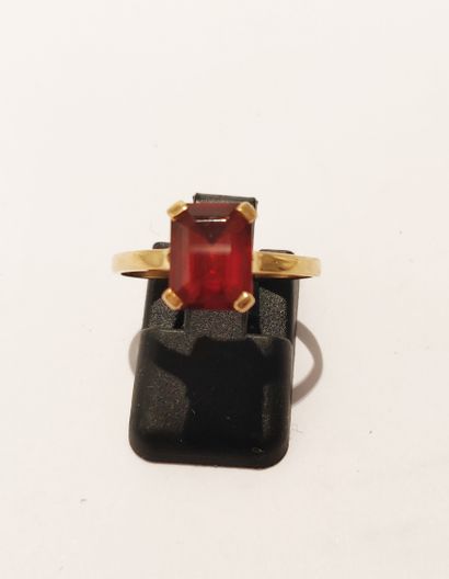 null 18K (750/1000) yellow gold ring set with an emerald-cut red stone in a flat...