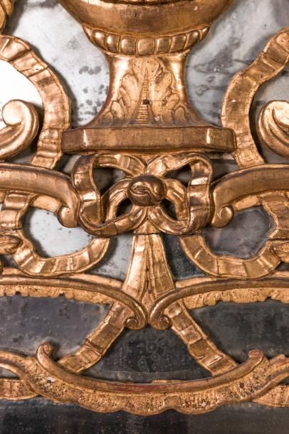  Un miroir en bois doré à décor ajouré de nœuds de ruban, vases néoclassique, feuillages,...