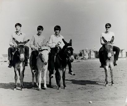 null Les Beatles sur des ânes sur une plage. Circa 1963. Tirage argentique sous passe-partout....