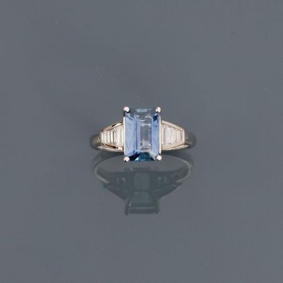 null White gold ring, 750 MM, adorned with an emerald-cut sapphire with cut sides...