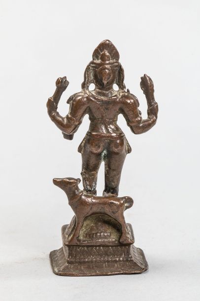 null Shiva Bhaïrava, debout sur un haut piédestal sous une forme à quatre bras tenant...