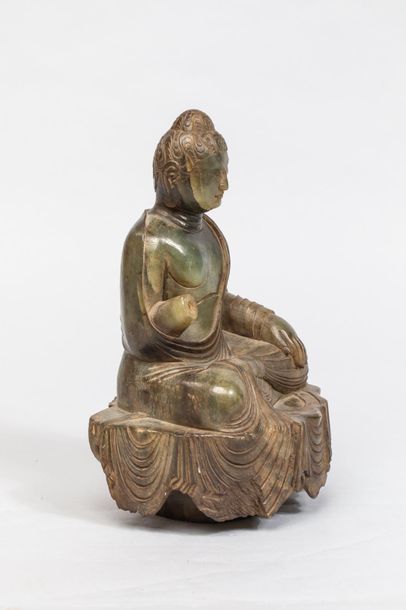 null Buddha assis sur une base couverte du textile drapé de sa robe monastique retombant...