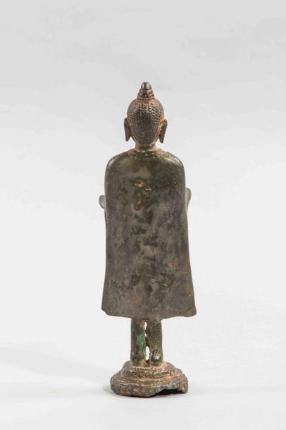 null Bouddha debout dans une posture hiératique sur un socle , sa robe monastique...