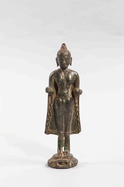 null Bouddha debout dans une posture hiératique sur un socle , sa robe monastique...