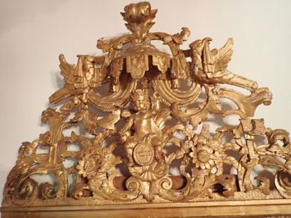 Glace en bois sculpté et doré surmontée d'un fronton ajouré représentant le triomphe...