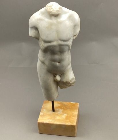 null Torso of an acephalous man in sculpted white marble. Resting on a yellow marble...