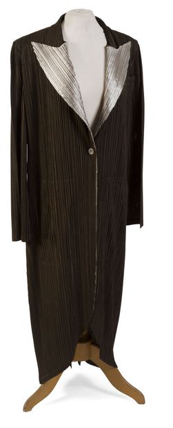 null ISSAYÉ MIYAKÉ, Pleats Please.
Long-sleeved coat and long skirt in brown polyester...