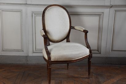 null A Louis XVI period moulded and carved natural wood cabriolet back armchair....