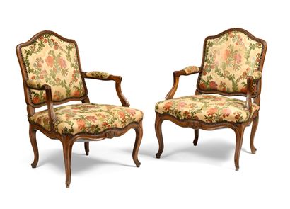 null A pair of flat-backed armchairs in moulded and carved walnut with stylised flowers;...