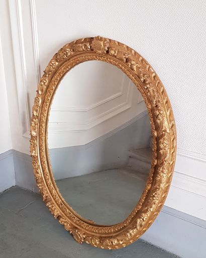 null * Miroir ovale dans un cadre en bois sculpté et doré à décor de guirlandes fleuries...