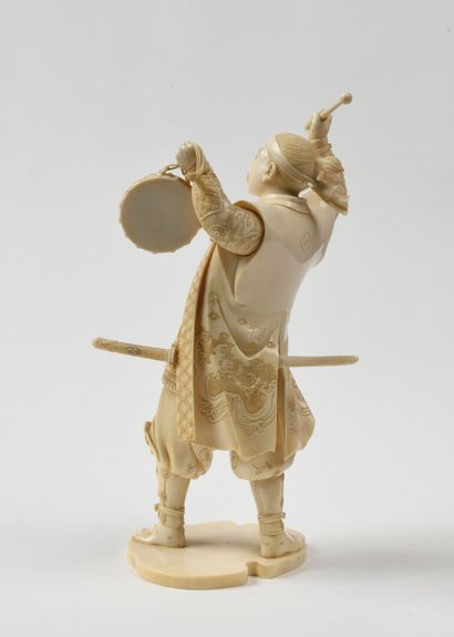 null JAPAN Carved ivory figurine representing a samurai playing tambourine, standing...
