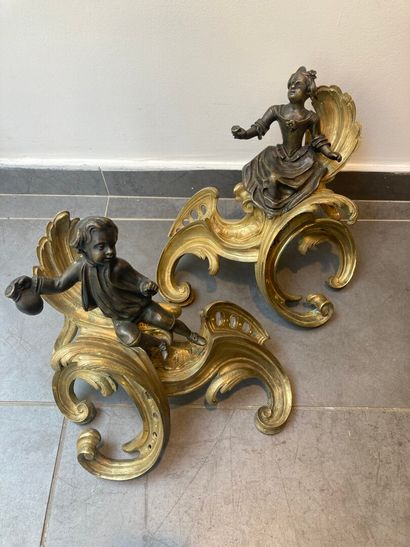 null A pair of Louis XV style Chenets in chased bronze with two patinas decorated...