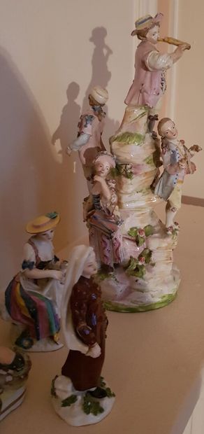 null Four polychrome porcelain groups featuring a child musician on a mound, a hunter...