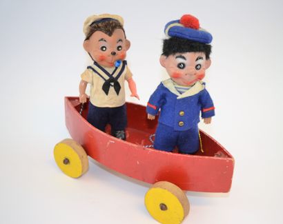 null Deux poupées en celluloïde en tenue de marin avec une barque en bois sur roulette....