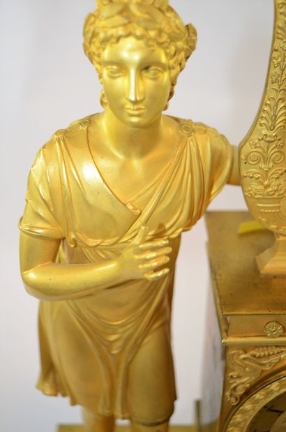 PENDULE EMPIRE Pendule Empire en bronze doré, avec personnage et attribut de musique...