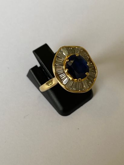 null Bague en or jaune 750 millièmes ornée d'un saphir ovale dans un entourage formant...