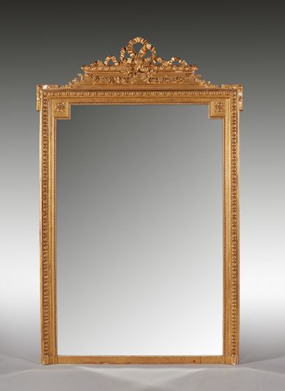 null Grand miroir en bois doré, le fronton à décor de noeuds de ruban et guirlande...