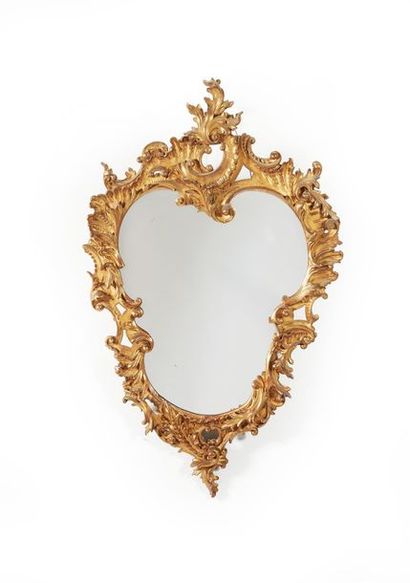 null Miroir en bois sculpté et doré de forme Rocaille à décor de rinceaux feuillagés....