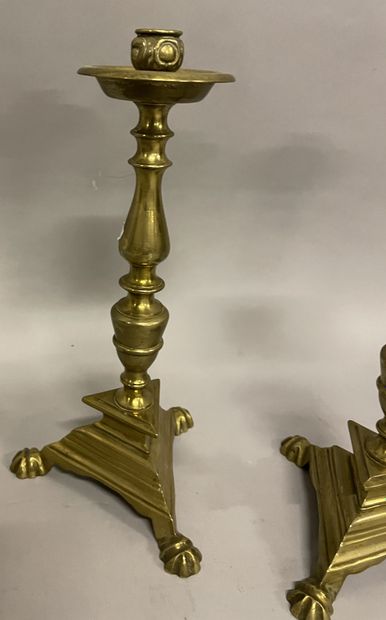 DEUX BOUGEOIRS en laiton style Régence TWO brass CANDLES resting on a triangular...