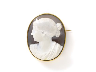 Broche en or 750 millièmes, ornée d'un camée agate 2 couches sculpté du profil gauche d'une femme coiffée en buste. Avec épingle et chaînette de sécurité. Travail français de la seconde moitié du XIX° siècle.