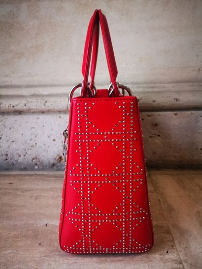 CHRISTIAN DIOR Sac modèle Lady Dior en cuir rouge, le motif cannage clouté. Garniture...