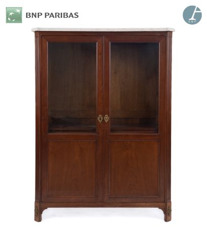 null Bookcase in natural wood and veneer, opening by two glass doors in front, the...