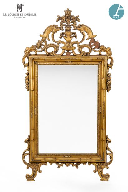 null Large gilded and carved wood mirror, decorated with scrolls and volutes, topped...