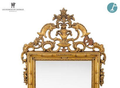 null Large gilded and carved wood mirror, decorated with scrolls and volutes, topped...