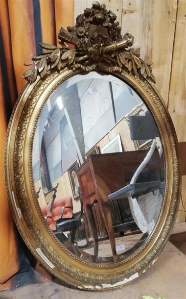 null MIROIR ovale en bois et stuc doré surmonté d'une couronne de fleurs, noeud rubannés,...