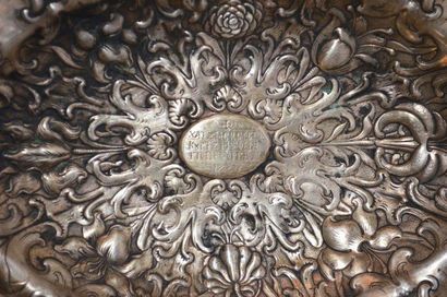null Plat ovale en argent repoussé d'un décor floral, présentant au centre une inscription...