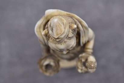 null JAPON. Divinité en ivoire sculpté tenant une fleur de lotus dans la main droite...