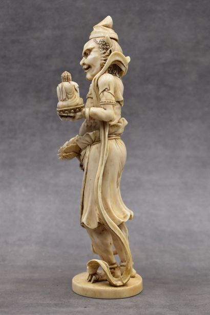 null JAPON. Divinité en ivoire sculpté tenant une fleur de lotus dans la main droite...