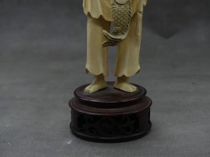 null CHINE. Pêcheur en ivoire sculpté sur une base en acajou. Sur socle en acajou...